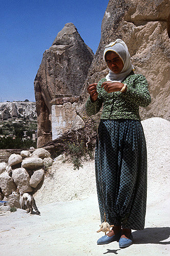 Girl spinning wool  outside cone dwelling Cappadocia, Turkey